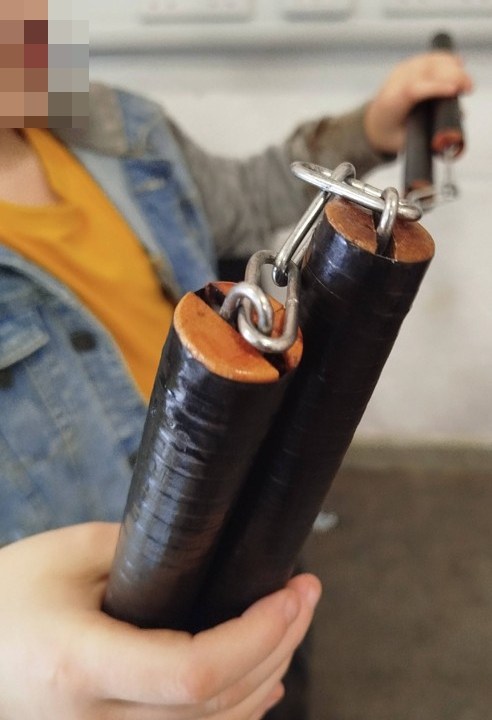 A young person holding a pair of homemade nunchucks.