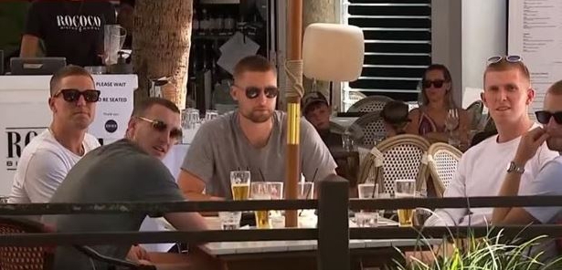 English cricketers sitting at an outdoor restaurant in Australia.