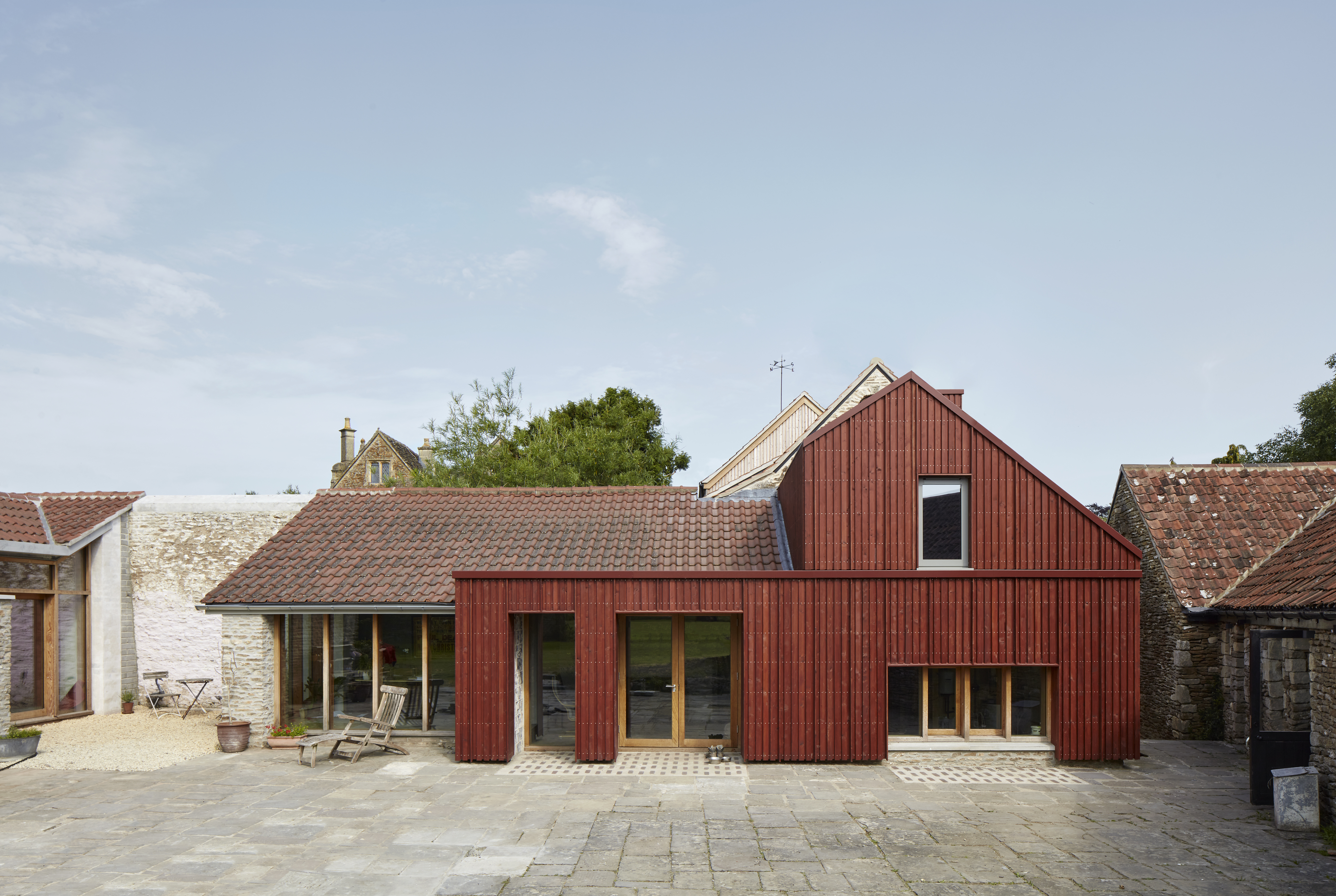 The Wool Hall building features a modern red-sided extension with a pitched roof, next to a building with a traditional tiled roof and stone walls.
