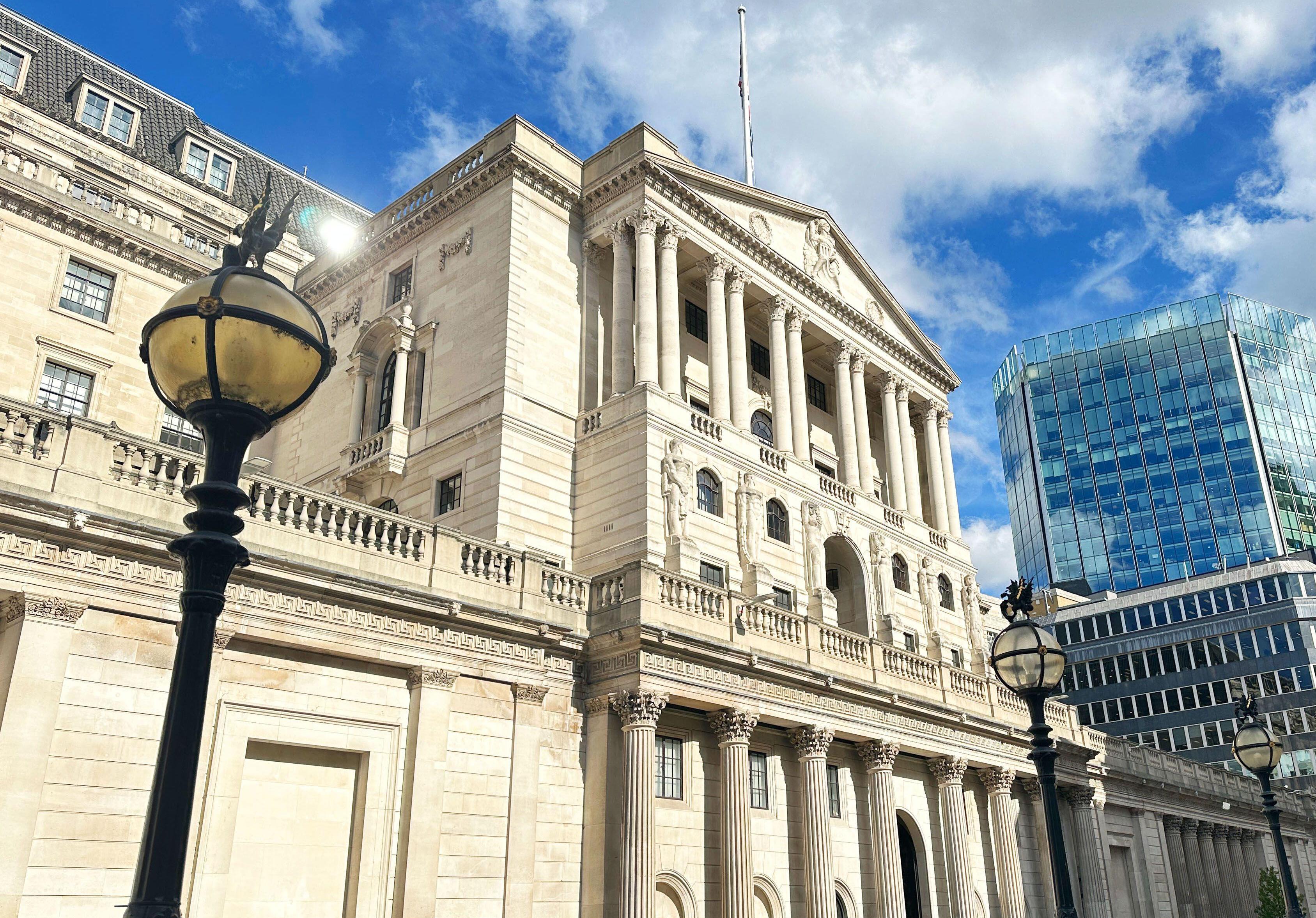 The Bank of England building under a blue sky with some clouds.