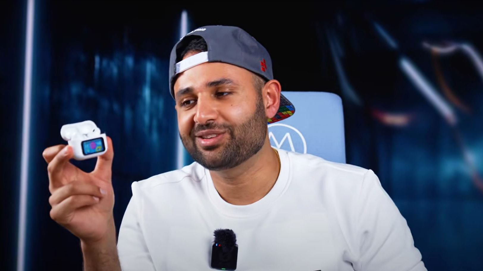 Arun Rupesh Maini, also known as MrWhoseTheBoss, holding a white AirPod case with a small screen.