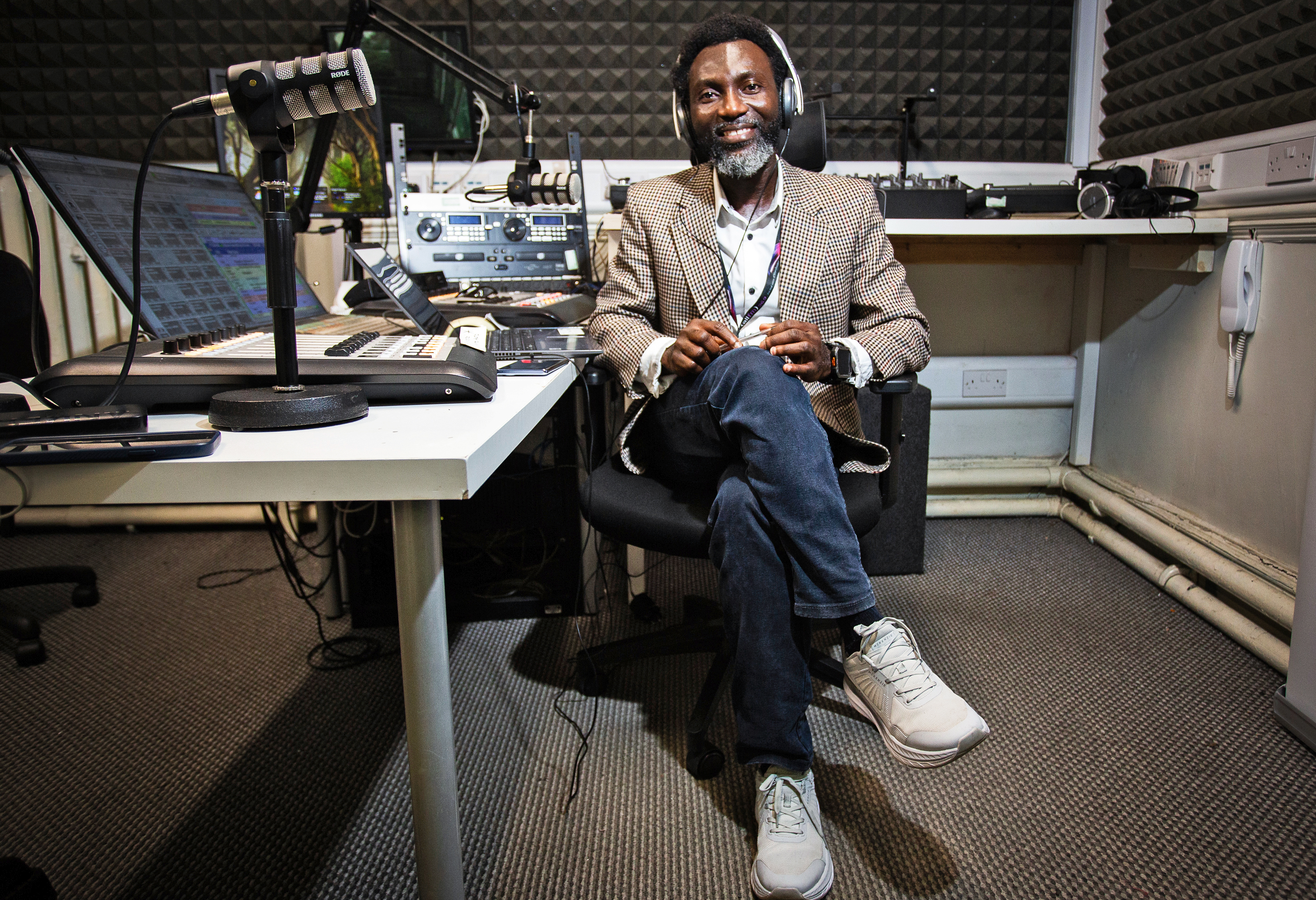 Presenter Jacob Quarm sits at a radio station desk with headphones and a microphone.