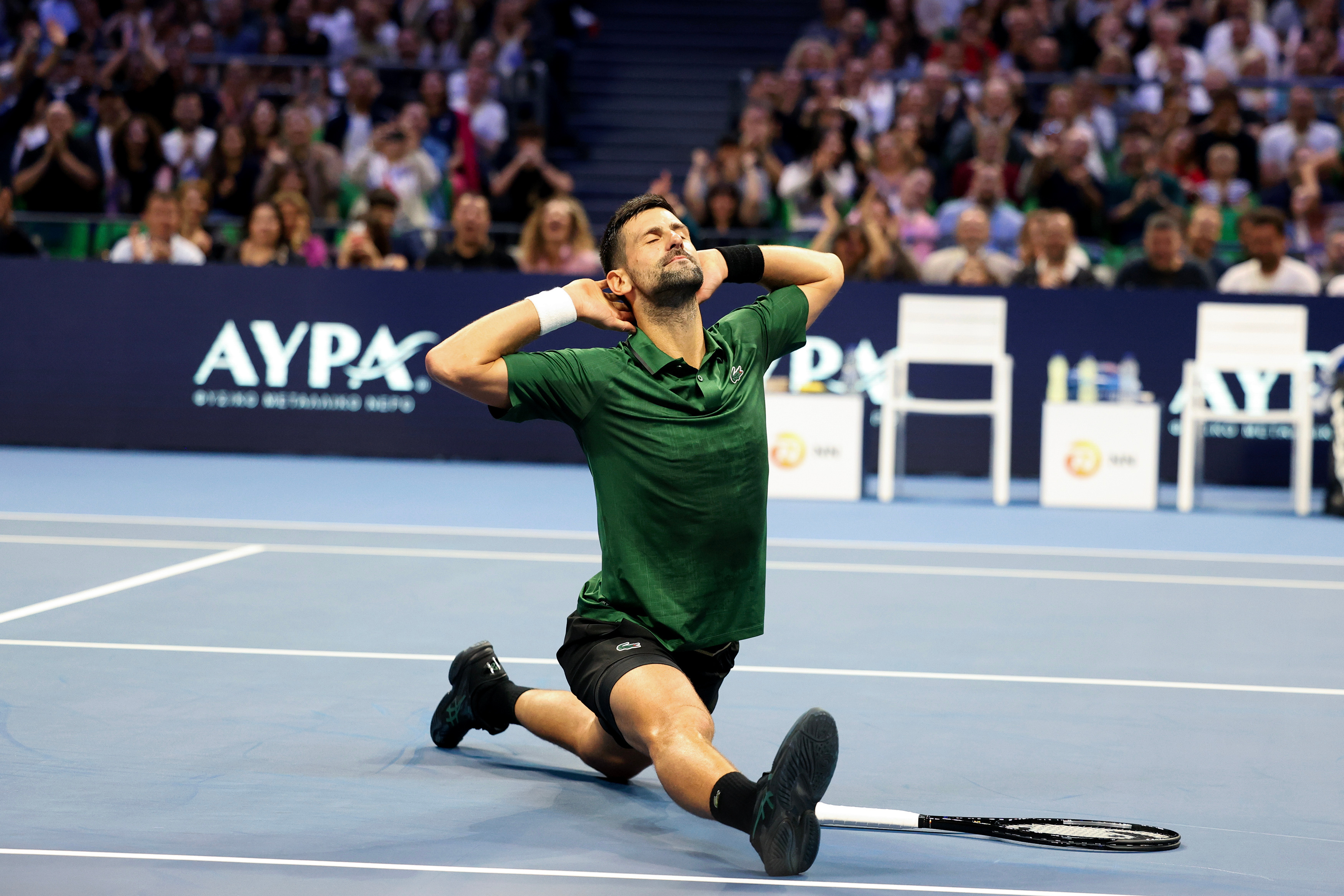 Novak Djokovic in a deep lunge on a tennis court.