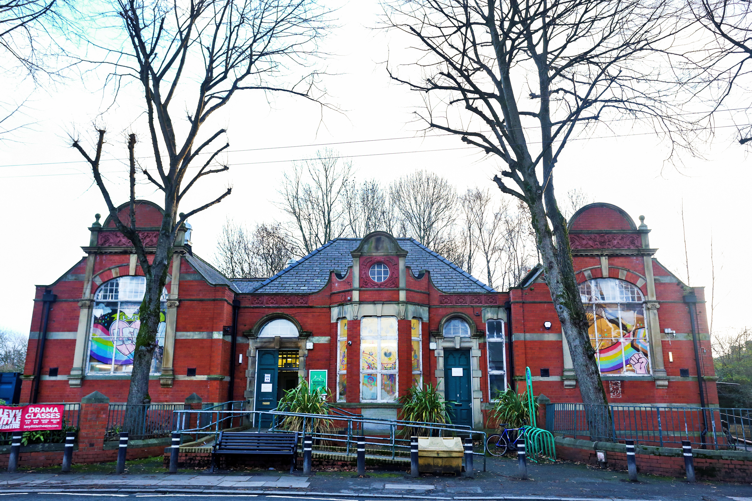 Levenshulme Old Library in Manchester, a red brick building with colorful window decorations and a bicycle rack.