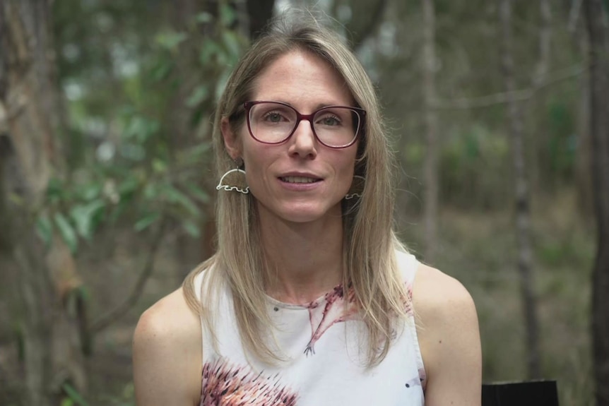 A woman sitting in the bush wearing echidna earings