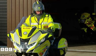 A south west blood bike rider sat on a motorbike in front of the charity's Devon headquarters in Plymouth