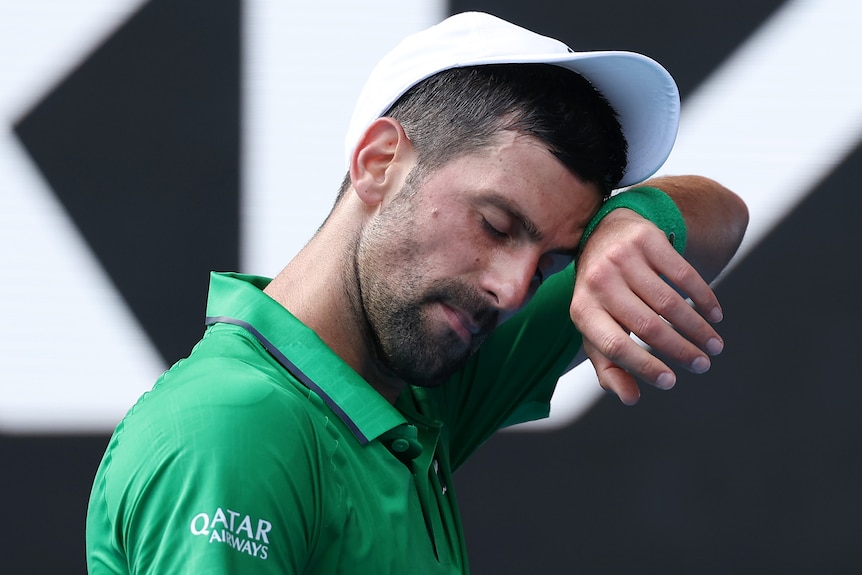 Novak Djokovic wipes his fact at the Australian Open.