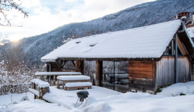 A restored alpine refuge overlooks Annecy from a wooded trailhead