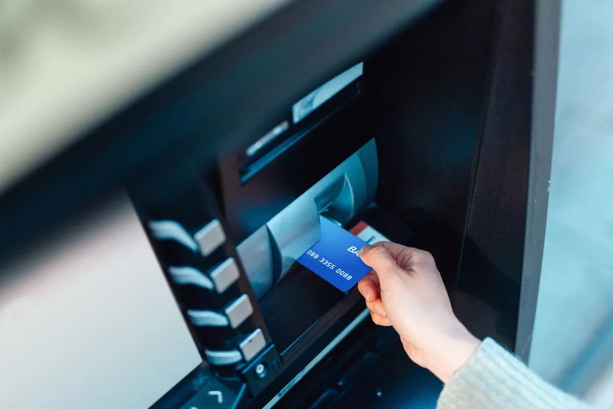 Young woman at the automatic cash machine (ATM) on city street.
