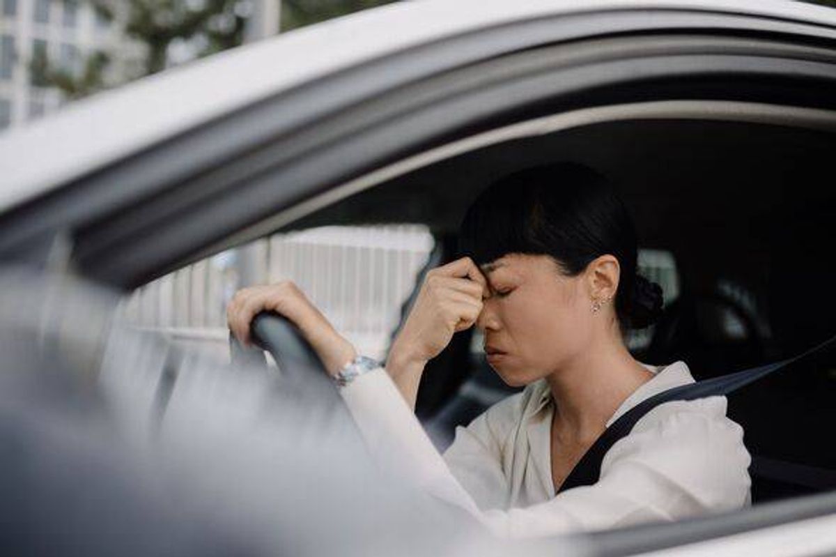 Frustrated Japanese woman sitting in her car during a traffic jam.