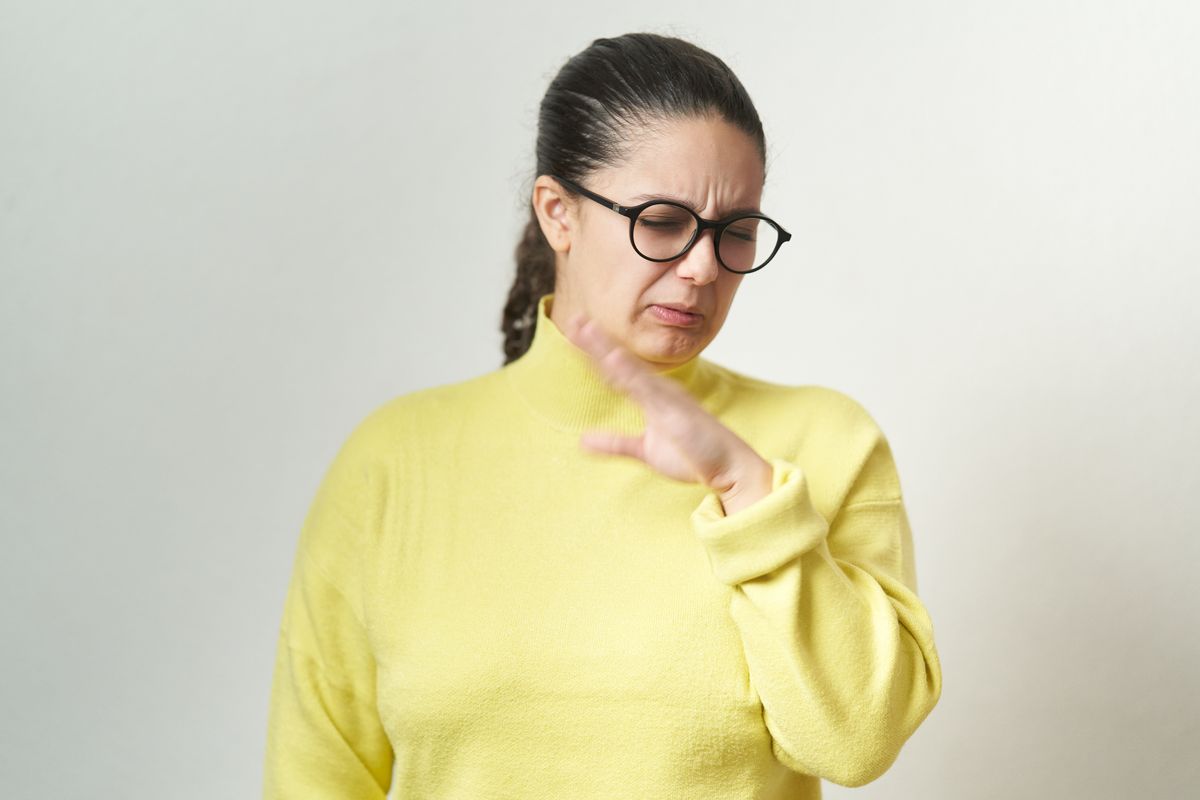 Young woman in eyeglasses feeling disgusted and complaining while standing an isolated background.