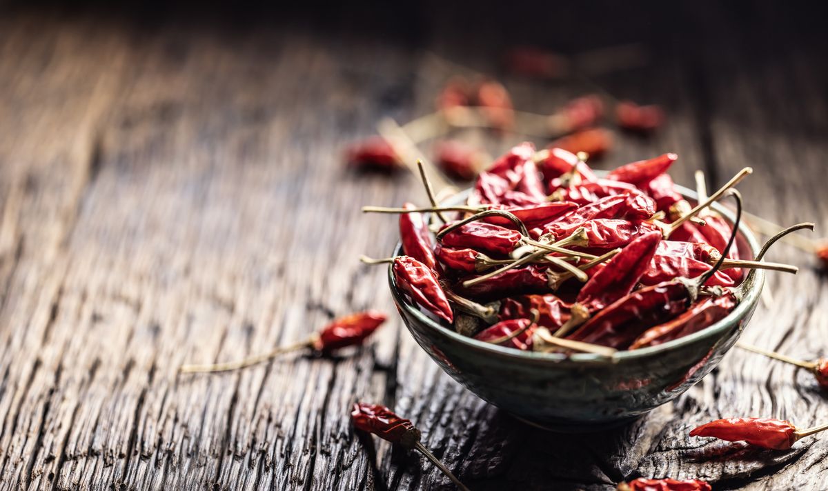 Dried chili peppers in a bowl on a rustic table.