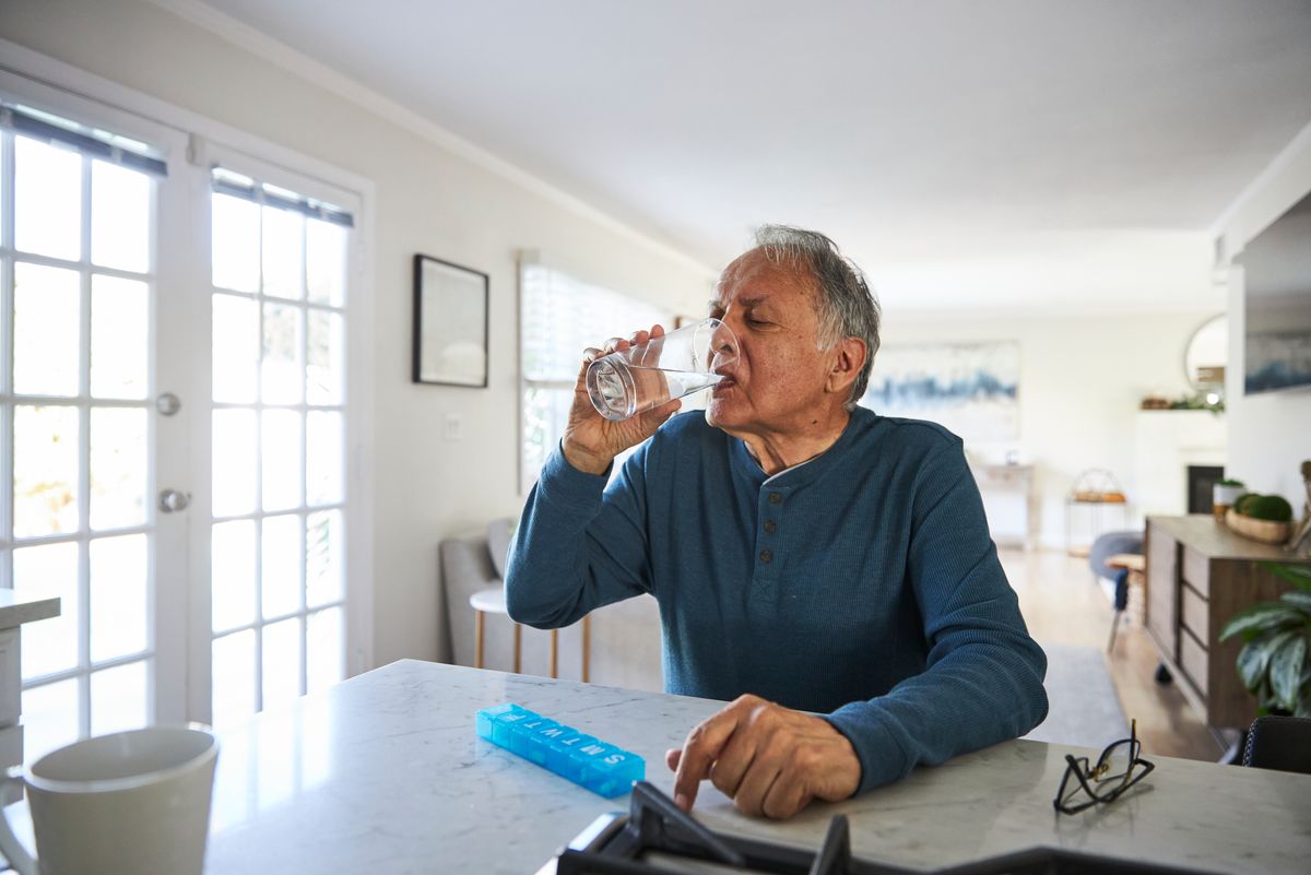 Senior man taking medicine at home