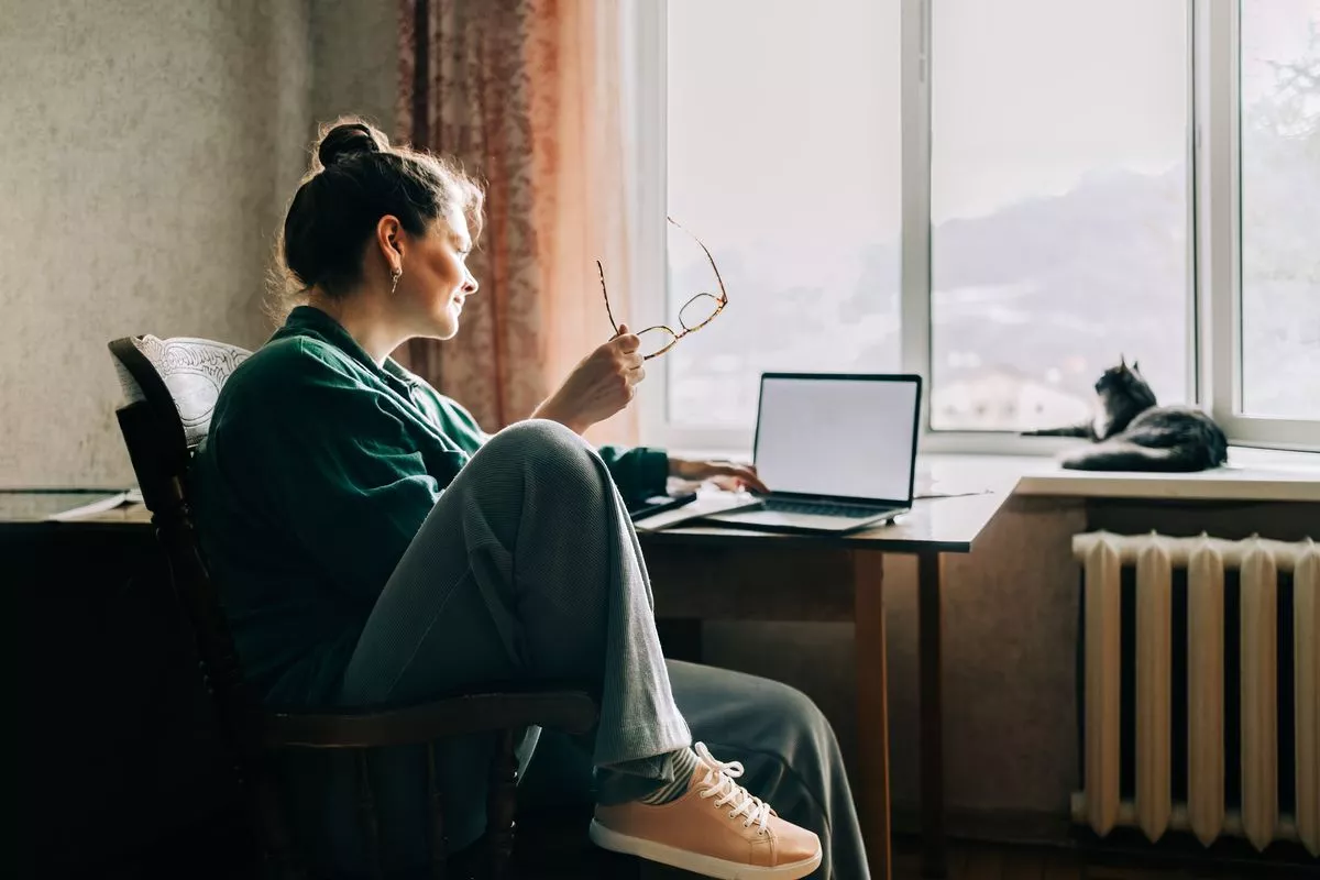 Woman working from home with cat on window sill