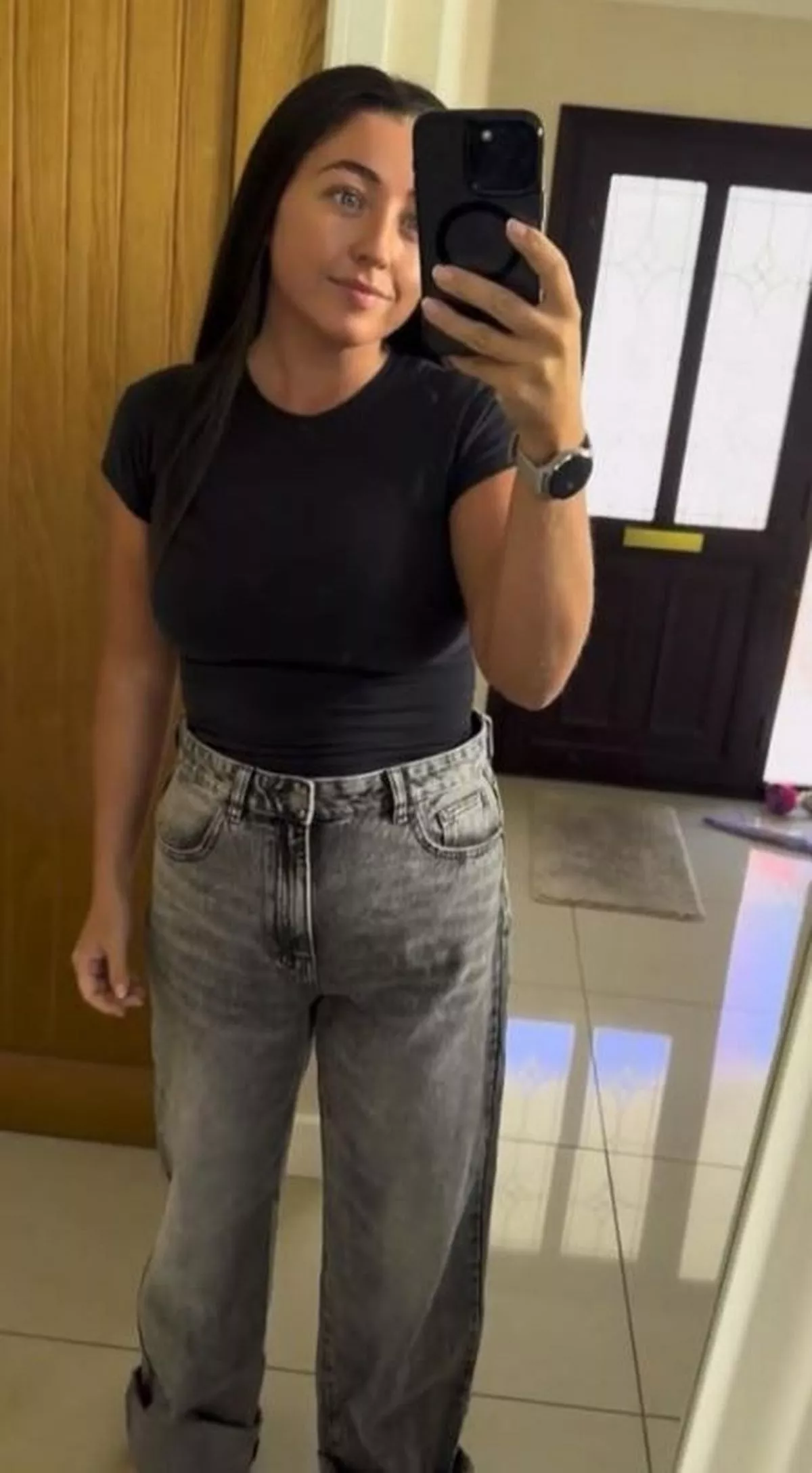 A dark-haired woman in jeans and a black T-shirt