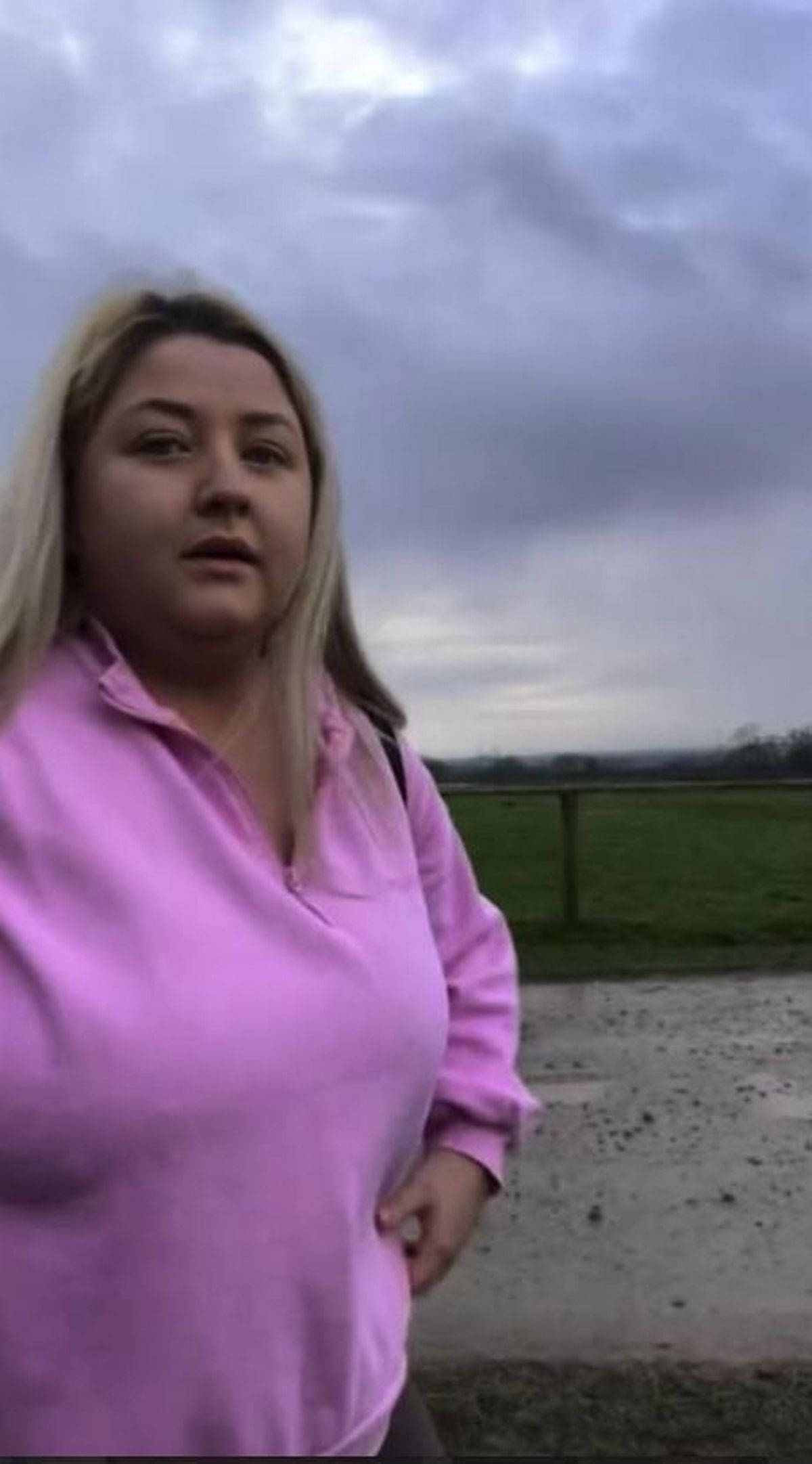 A blonde woman wearing a pink jumper