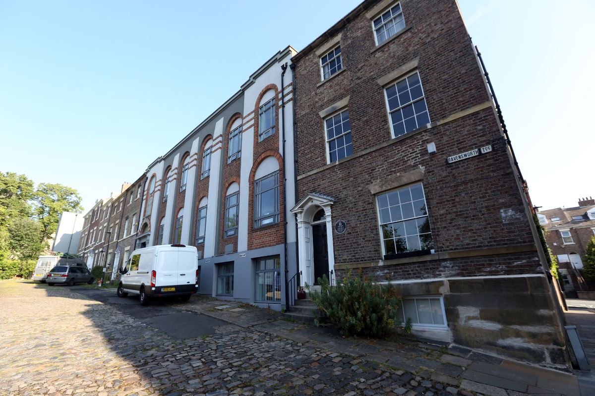 A van parked on a cobbled street outside a tall row of Georgian terraced houses