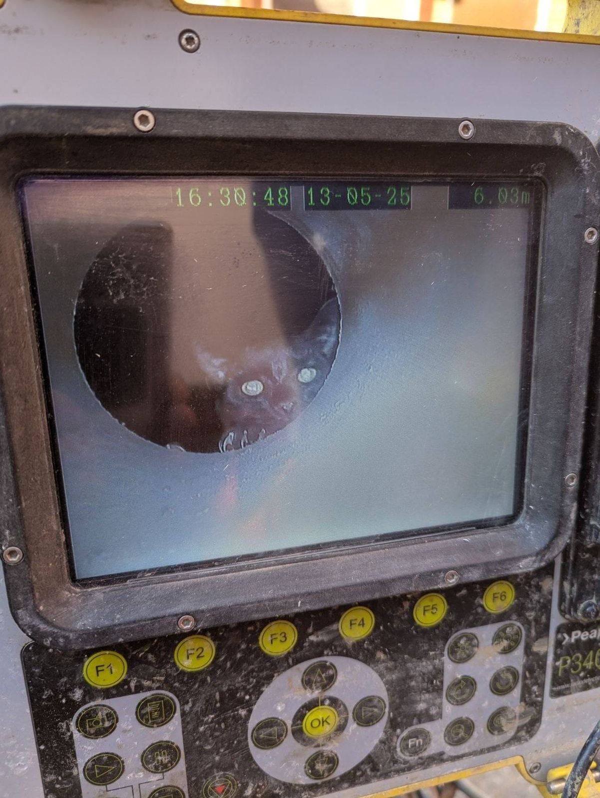 A close-up of an electronic device featuring a circular screen displaying a reflection, with a series of yellow buttons and a control panel in the foreground.