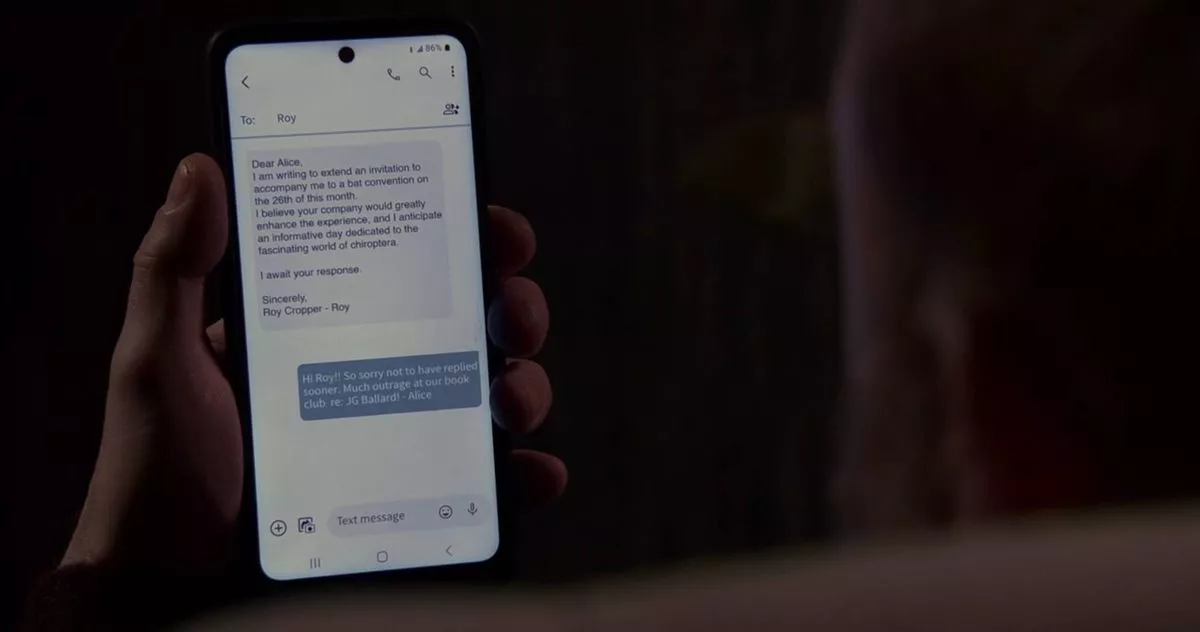 An individual is holding a smartphone displaying a text-based interface with a prominent blue button, suggesting an interaction or selection process within a digital application.