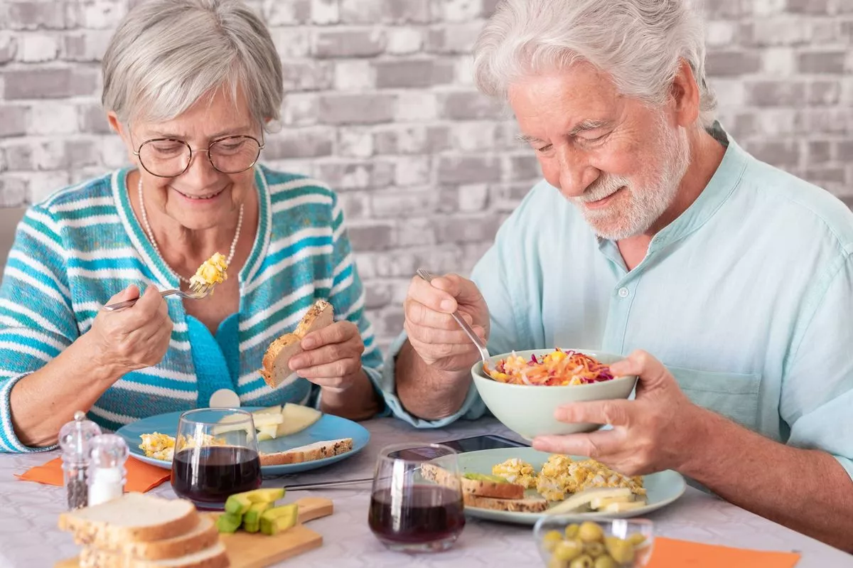 Happy elderly couple eating food together. 