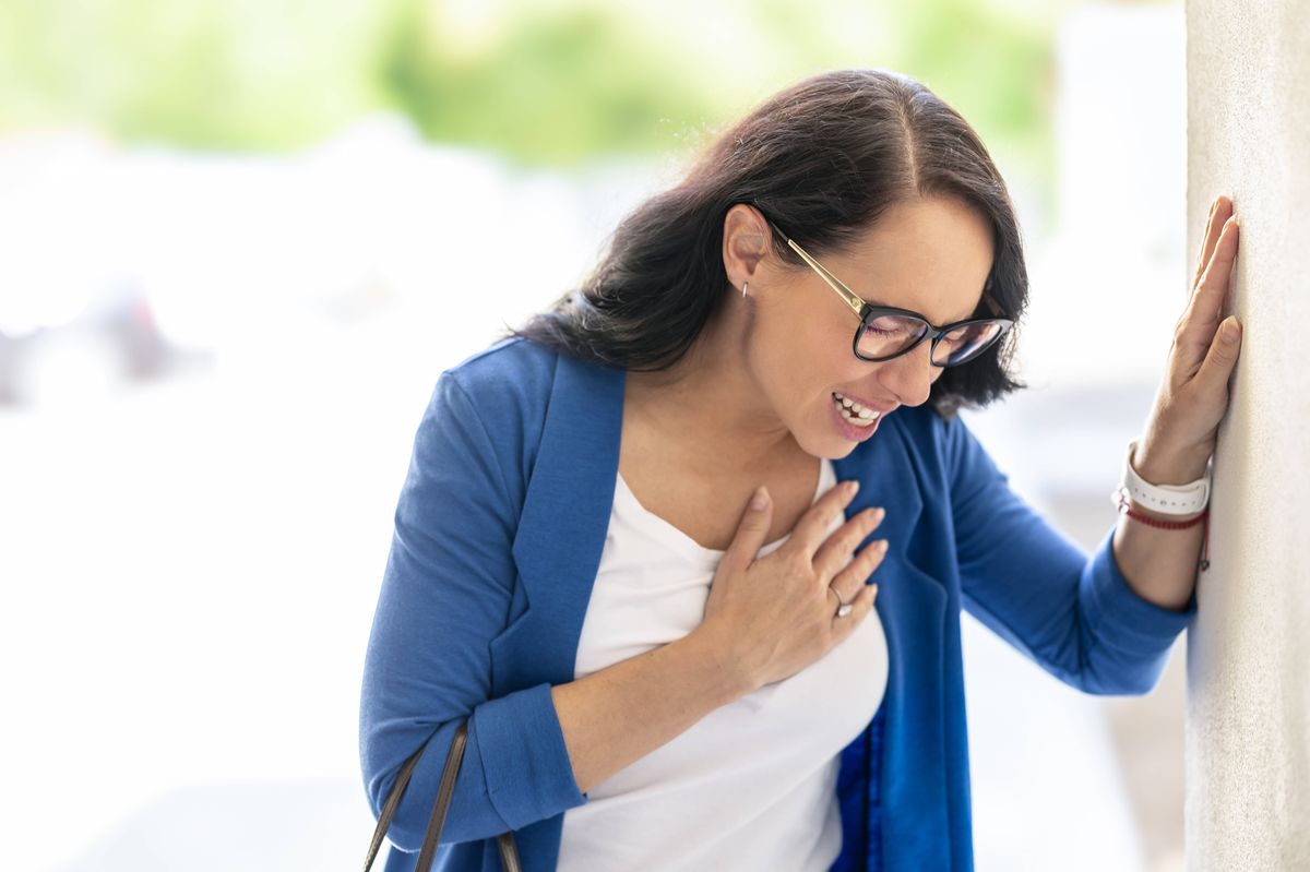 Young business woman with hands on chest with heart attack or arrhythmia.