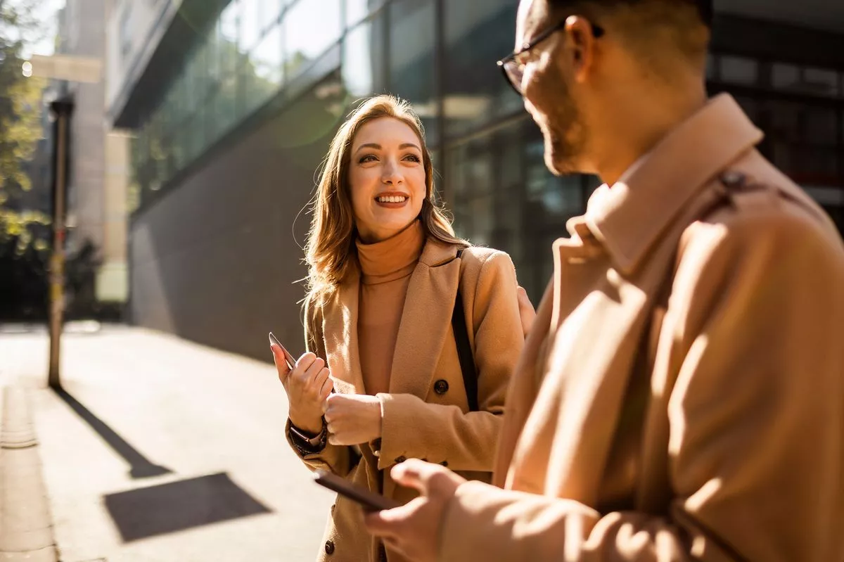 A woman in morning sunlight talks to a colleague