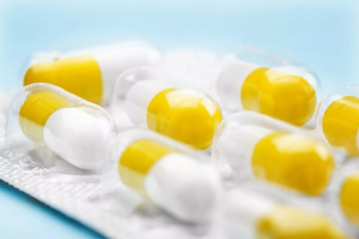 white and yellow pills in a silver plastic packaging