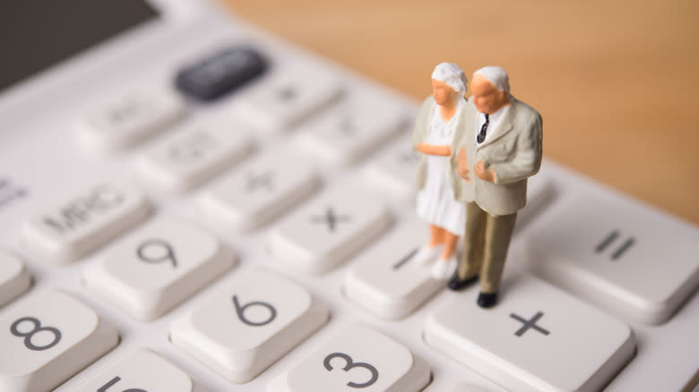 Senior figurines standing on a calculator