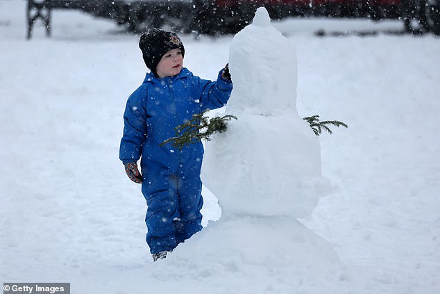 A child builds a snowman in the snow in Ballater, Scotland, where amber warning are forecast