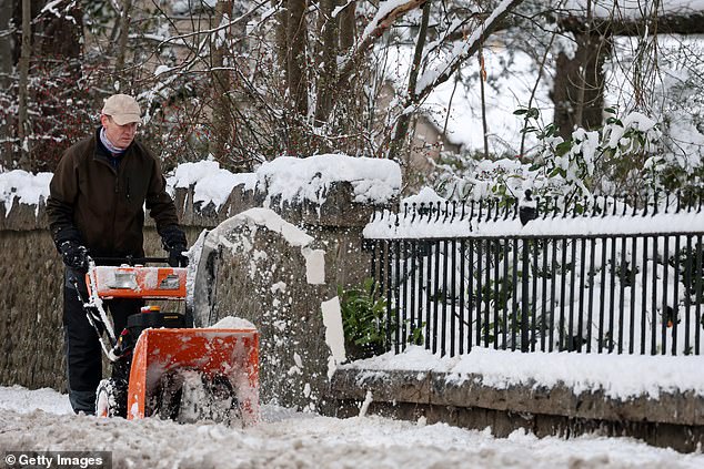 A man takes to the street to clear up snow amid the amber weather warning being issued