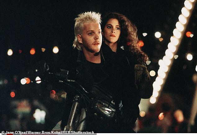 His profile increased substantially with Joel Schumacher's teen vampire film The Lost Boys (1987), and other early films included 1988's Young Guns, as well as Flatliners (1990), which paired him with Julia Roberts and Kevin Bacon; pictured in The Lost Boys with Jami Gertz