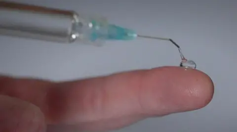 BBC News A blob of the clear gel on a fingertip, showing its viscosity and transparency.