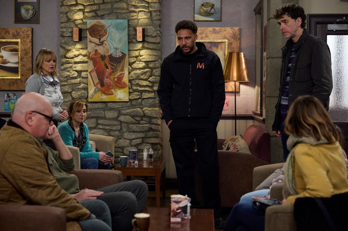 Billy, Marlon and Nicola stand over Laurel, Paddy, Dylan, Rhona and April in the cafe in a scene from Emmerdale