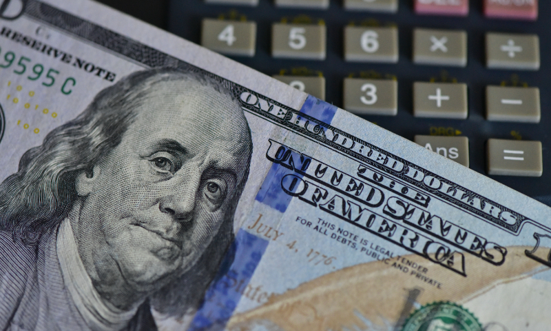 An illustration show a US dollar bill and a calculator at a bank in Fuyang, East China