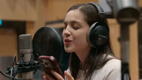 Warchild Olivia Rodrigo sings while reading lyrics from her phone