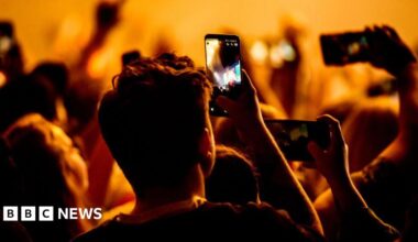 A crowd film a concert on their phones