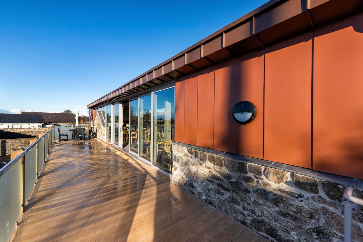 The wraparound deck is perfect for sunny days and also for accessibility  at The renovation, conversion and transformation of T'yn Llan commnity pub in Llandwrog, Gwynedd this is the new build extension with restaurant, catering kitchen, facilities and community room