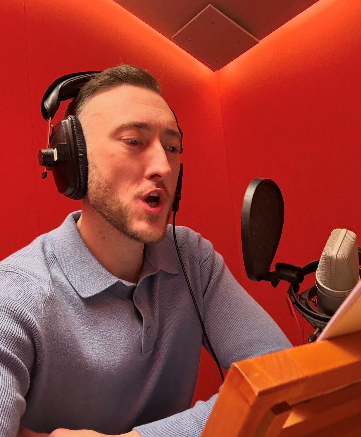 Brett Harman speaking into a microphone while doing voice acting