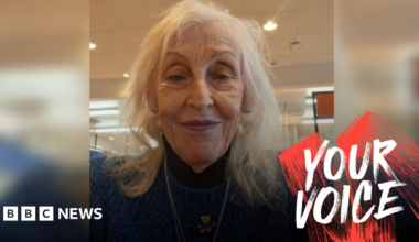 A picture of a woman with shoulder-length grey hair in a blue jumper