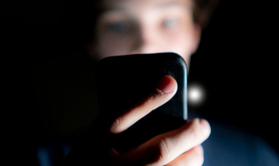 Man using phone in dark.
