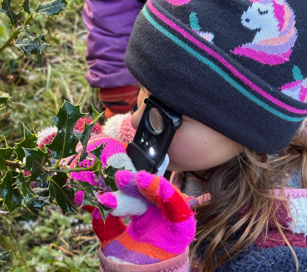Girl looking at holly through a magnifying lens