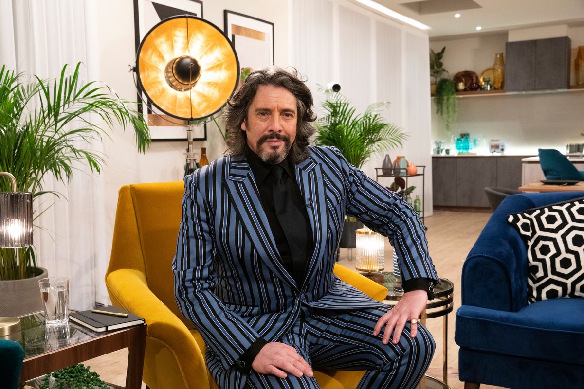 Laurence Llewelyn-Bowen sits on a chair in front of a huge clock