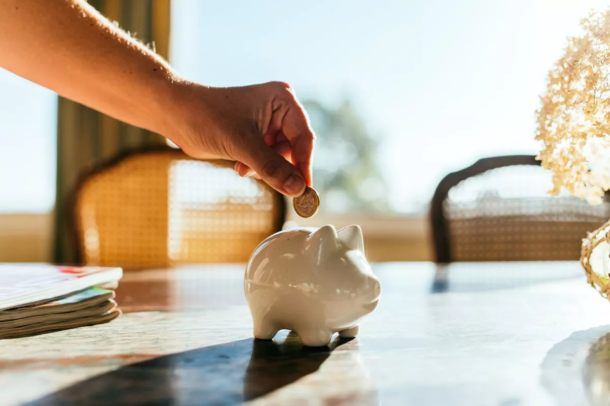 Woman putting savings in a white piggy bank.