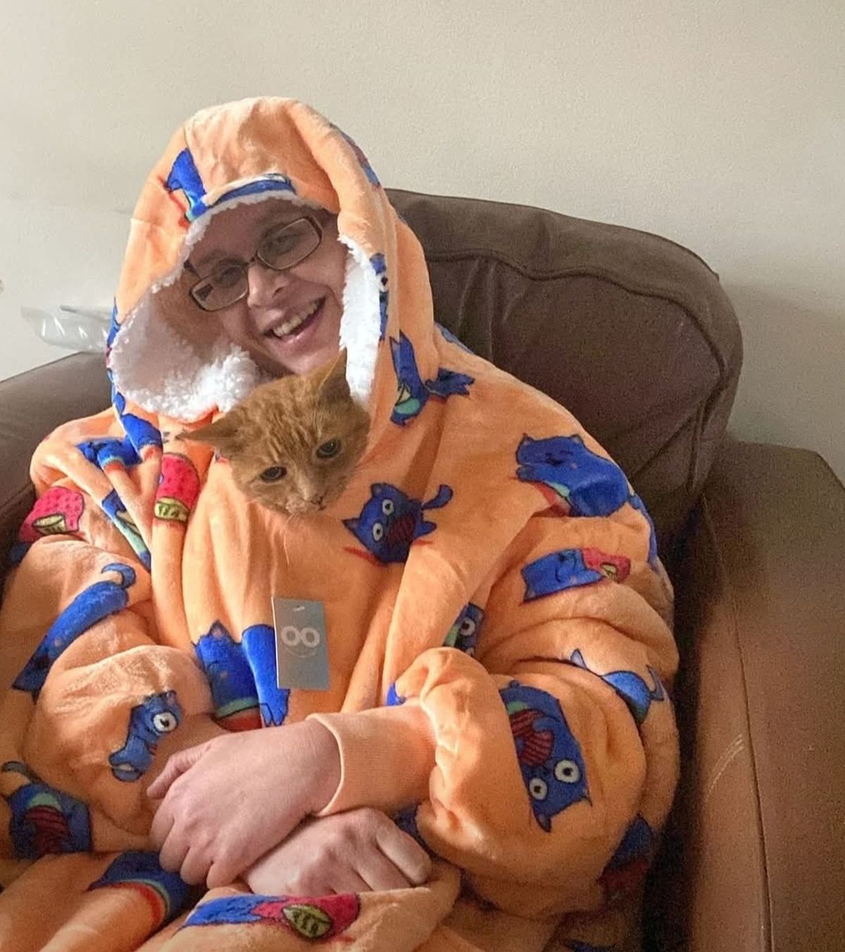 Clare sat wrapped up in a chair with a ginger cat