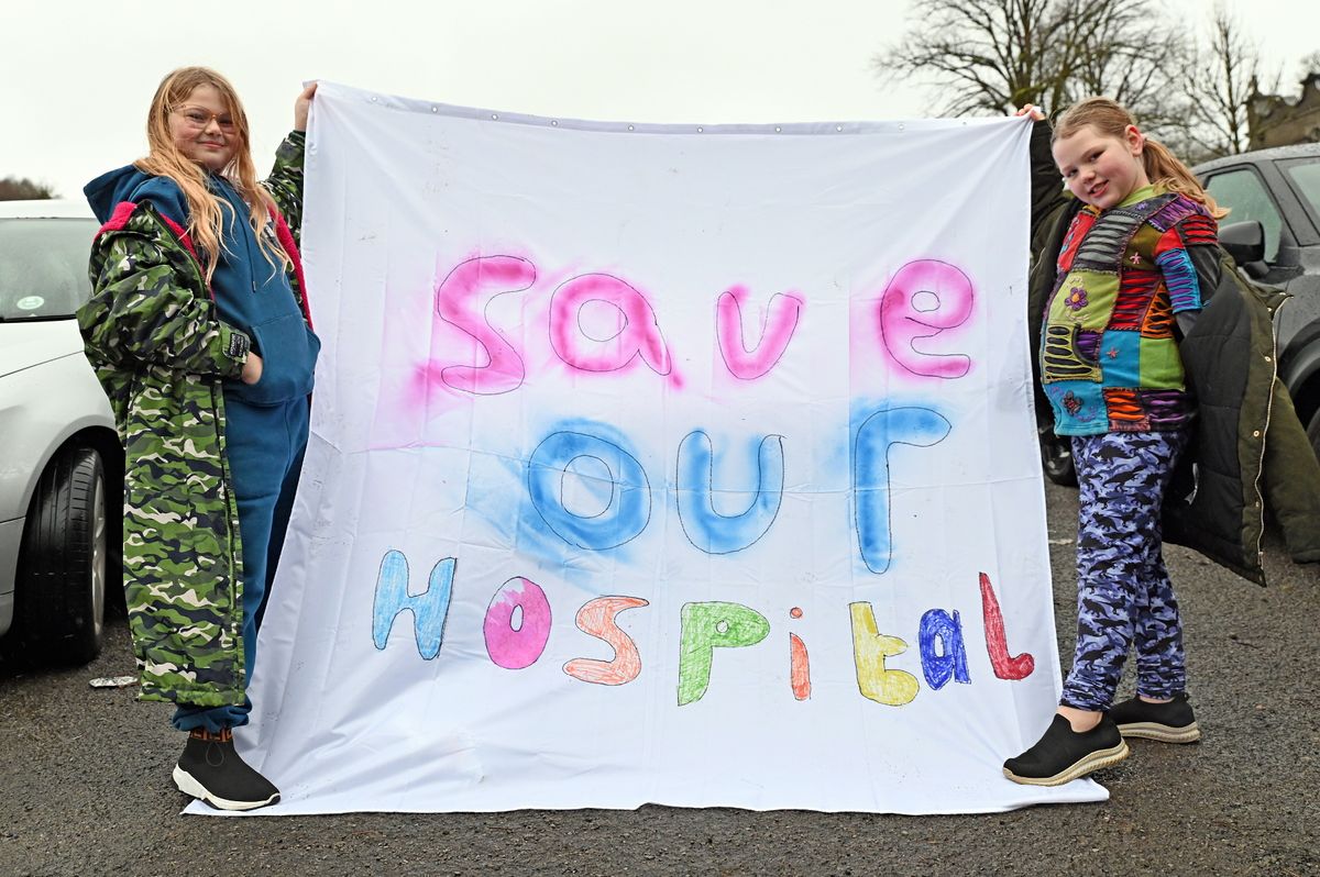 Two women holding up a sign saying "save our hospital".