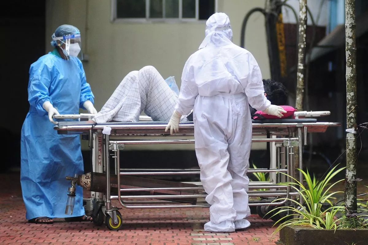 Health workers wearing protective gears to move a man with symptoms of Nipah virus in 2023