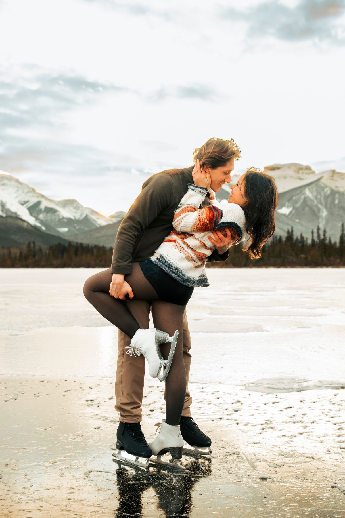 vanessa bauer with leg up holding fiance on frozen lake