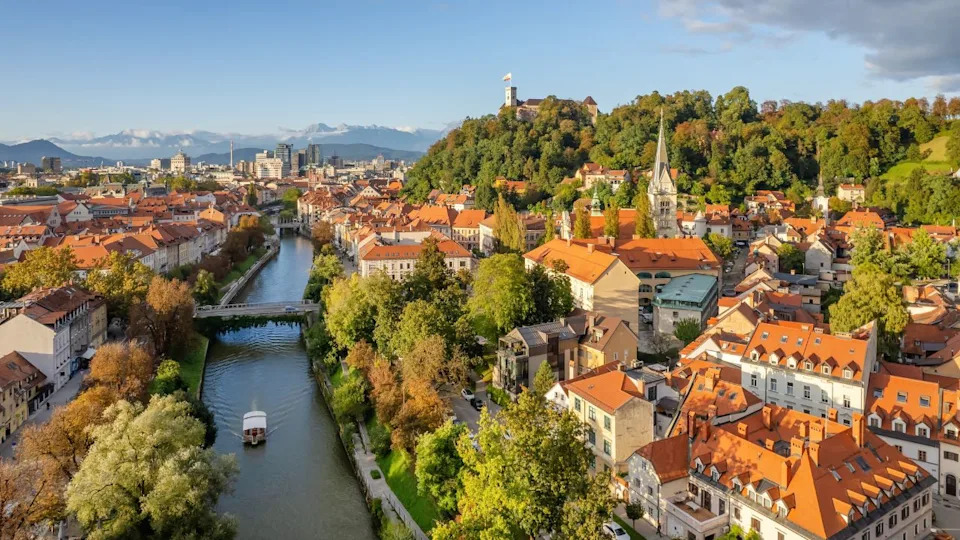 Aerial view of the Ljubljana old town at autumn, Slovenia. Ljubljana castle, historic buildings and Ljubljanica river in Slovenian capital at sunny day. Beautiful mountain range at background