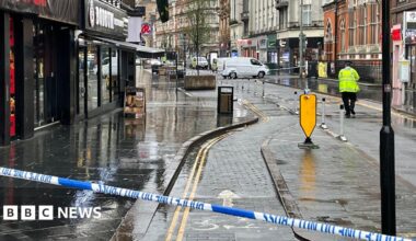 Police cordon tape across Granby Street in Leicester. A police officer stands at the scene.