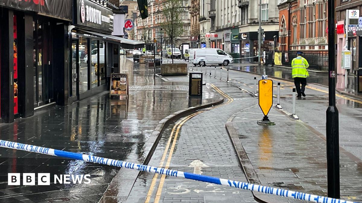 Police cordon tape across Granby Street in Leicester. A police officer stands at the scene.